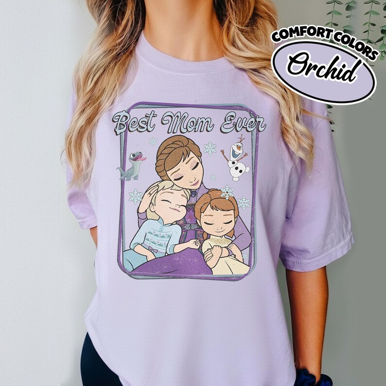 May include: A light purple t-shirt with the words "Best Mom Ever" and a cartoon image of a mother and two children. The shirt also features the words "Comfort Colors" and "Orchid" in a white oval.