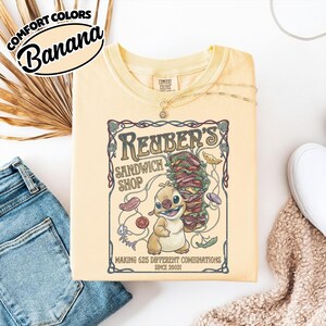 K&ouml;nnte beinhalten: Hellgelbes Comfort Colors T-Shirt mit einer Grafik f&uuml;r "Reuben's Sandwich Shop", einer Cartoonfigur und einem gro&szlig;en Sandwich. Der Text lautet "Making 625 Different Combinations Since 2003!"