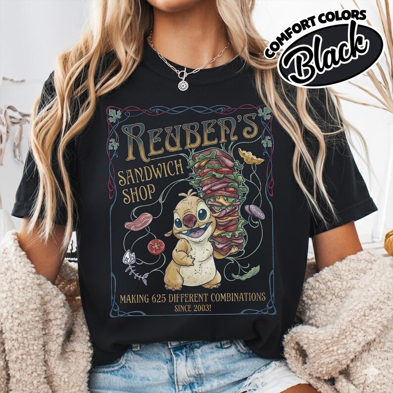 K&ouml;nnte beinhalten: Schwarzes T-Shirt mit einer Cartoonfigur, die ein gro&szlig;es Sandwich h&auml;lt. Das Shirt zeigt den Text "Reuben's Sandwich Shop" und "Making 625 Different Combinations Since 2003!" in einem dekorativen Rahmen. Die Worte "Comfort Colors" und "Black" sind in einem Kreis.