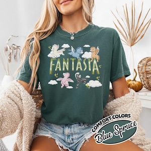 May include: A dark teal t-shirt featuring the word "Fantasia" in gold lettering and cartoon pegasus figures. The shirt also has the words "Comfort Colors" and "Blue Spruce" in a circular design.