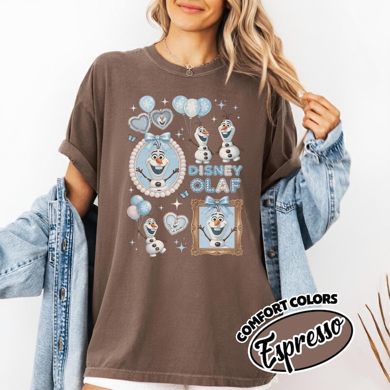 May include: Brown t-shirt featuring a Disney Olaf graphic. The design includes Olaf, balloons, and the text "Disney Olaf" in blue. The shirt has a Comfort Colors Espresso label.