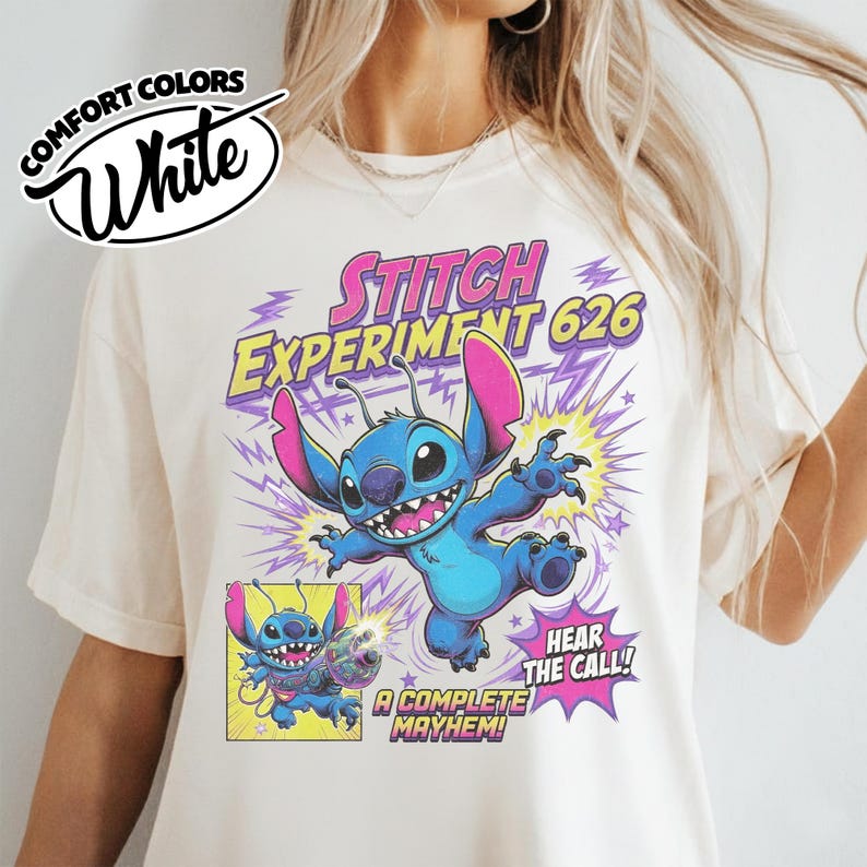 Może przedstawiać: Kremowy t-shirt z grafiką niebieskiej postaci Stitcha z Experiment 626. Wz&oacute;r zawiera fioletowe błyskawice, gwiazdki oraz napis Stitch Experiment 626, Hear The Call i A Complete Mayhem nadrukowany na przedniej części koszulki.