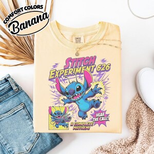 Może przedstawiać: Bladoż&oacute;łty t-shirt z grafiką przedstawiającą niebieską postać Stitcha z Eksperymentu 626. Wz&oacute;r zawiera fioletowe błyskawice, mniejszy panel w stylu komiksowym ze Stitchem oraz tekst Stitch Experiment 626, Hear the Call i A Complete Mayhem.