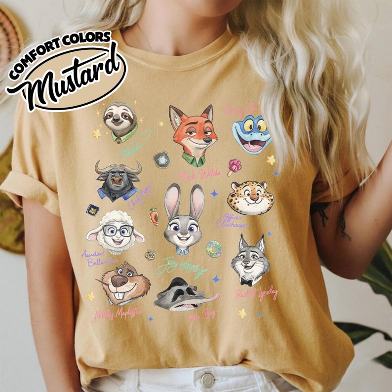 K&ouml;nnte beinhalten: Senffarbenes T-Shirt mit Illustrationen von Zeichentrickfiguren. Das Shirt enth&auml;lt den Text "COMFORT COLORS" und "Mustard" in einer stilisierten Schriftart. Das Shirt zeigt verschiedene Gesichter von Charakteren aus einem beliebten Animationsfilm.