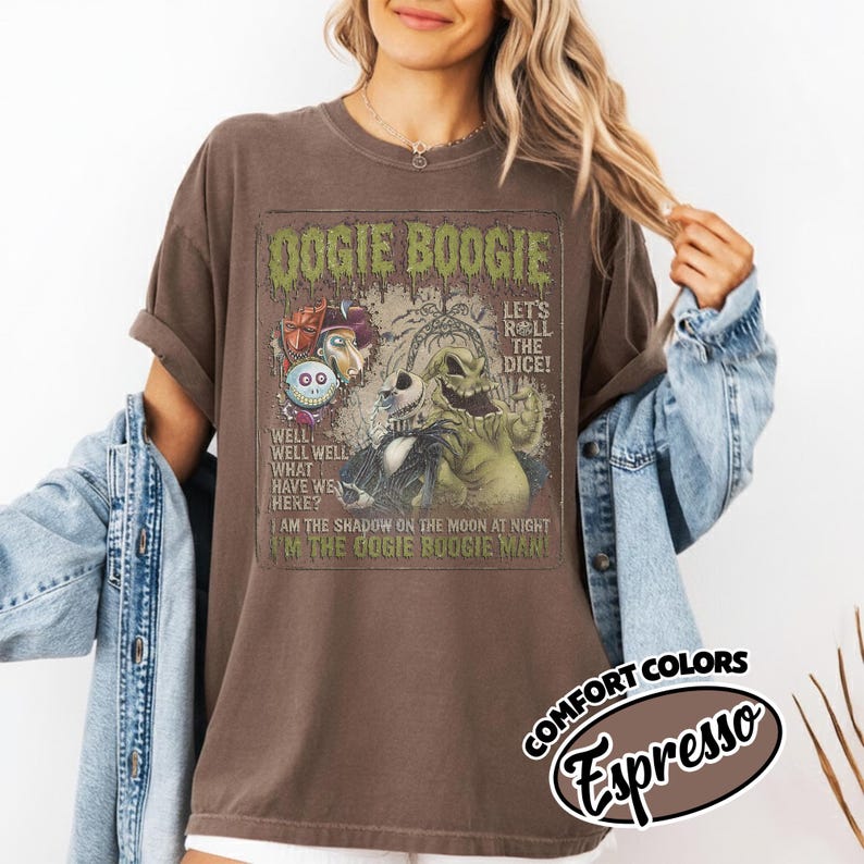 May include: Brown t-shirt with a graphic featuring the text "Oogie Boogie" and illustrations of characters. The shirt also has the text "Let's Roll the Dice!" and "I'm the Oogie Boogie Man!" The shirt is labeled "Comfort Colors Espresso".