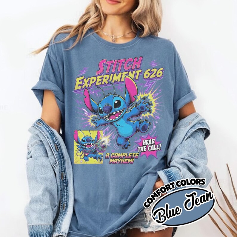 Może przedstawiać: Niebieski t-shirt z grafiką przedstawiającą postać Stitcha oraz napisem STITCH EXPERIMENT 626, HEAR THE CALL! i A COMPLETE MAYHEM!. Wz&oacute;r zawiera r&oacute;żowe i ż&oacute;łte akcenty, błyskawice oraz mały panel komiksowy.
