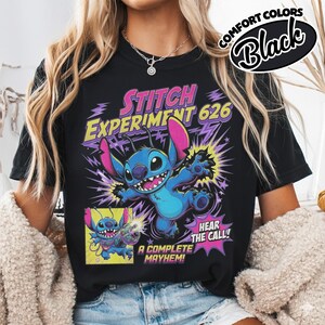 Może przedstawiać: Czarny t-shirt z grafiką niebieskiej postaci Stitcha z Eksperymentu 626. Projekt zawiera fioletowe błyskawice, tekst "STITCH EXPERIMENT 626", "HEAR THE CALL!" oraz "A COMPLETE MAYHEM!" z małym wstawionym panelem komiksowym.