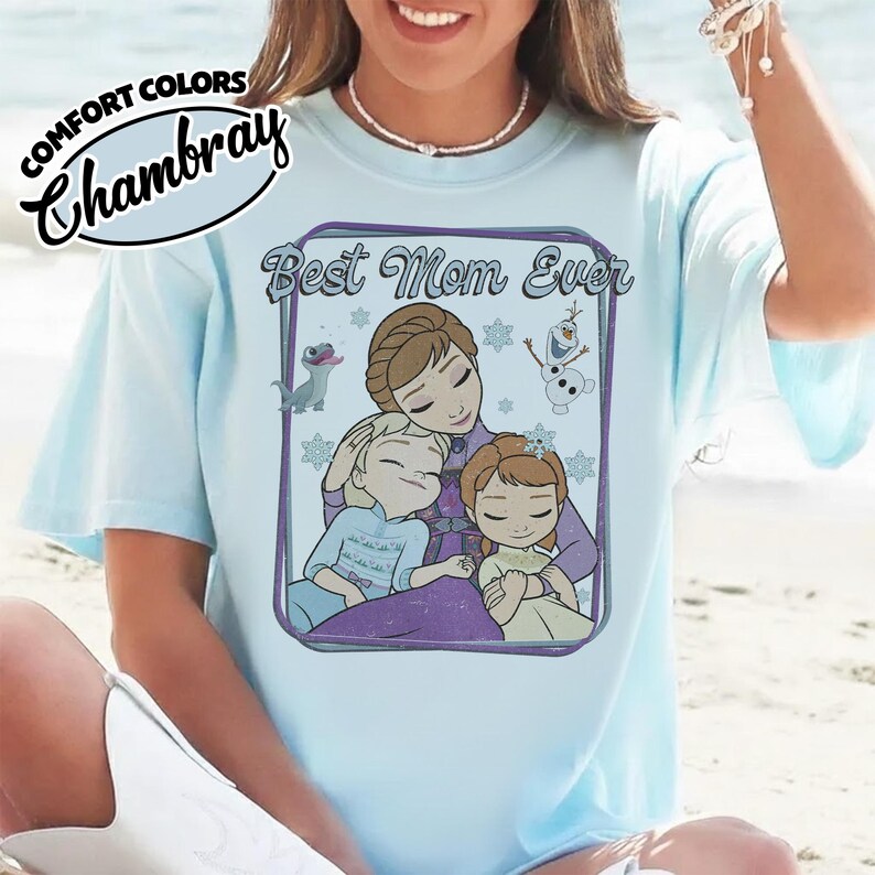 May include: Light blue t-shirt with the text "Best Mom Ever" and a graphic of a mother and two children. The shirt also features the text "Comfort Colors Chambray" in a cursive font.