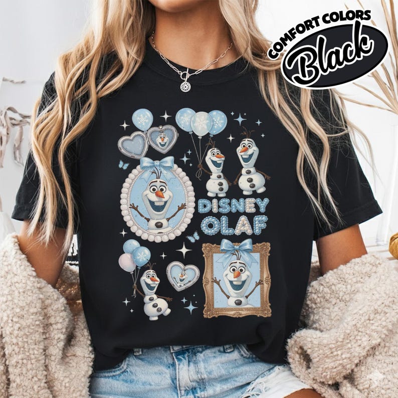May include: Black t-shirt featuring a Disney Olaf design. The graphic includes Olaf characters, balloons, and the text "Disney Olaf" in blue. The shirt has a crew neck and short sleeves. The words "Comfort Colors Black" are printed on the upper right.