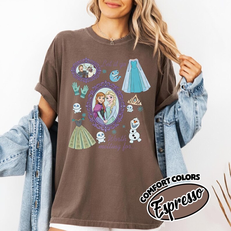 Op de afbeelding: Espresso-kleurig T-shirt met diverse illustraties uit een populaire animatiefilm. Het ontwerp bevat afbeeldingen van personages, jurken en sneeuwvlokken. De woorden "Let it go" en "Worth melting for" zijn ook zichtbaar. Het shirt maakt deel uit van de Comfort Colors collectie.