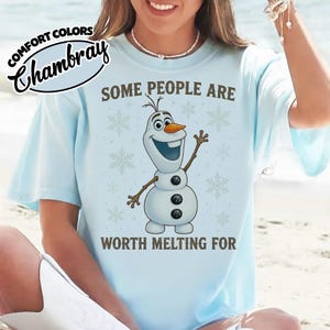 May include: Light blue t-shirt with the text "SOME PEOPLE ARE WORTH MELTING FOR" and a graphic of Olaf the snowman. The shirt also has the words "COMFORT COLORS" and "Chambray" printed on it.