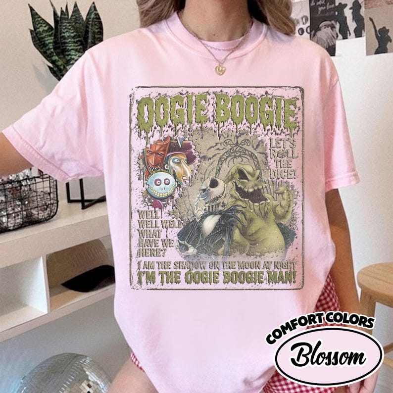 May include: A light pink Comfort Colors t-shirt featuring a graphic of Oogie Boogie from The Nightmare Before Christmas. The graphic includes text that reads "Oogie Boogie" and "I'm the Oogie Boogie Man!"