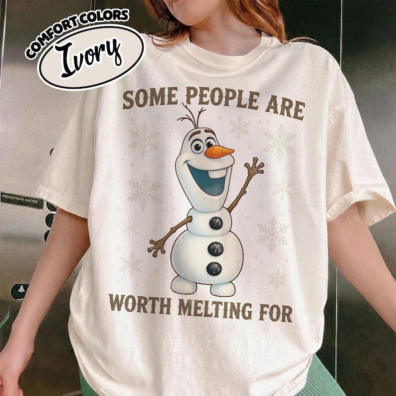 May include: Ivory-colored t-shirt featuring a cartoon snowman with the text "SOME PEOPLE ARE WORTH MELTING FOR." The snowman has a carrot nose, twig arms, and three black buttons. The shirt has a relaxed fit and is made of a soft material.