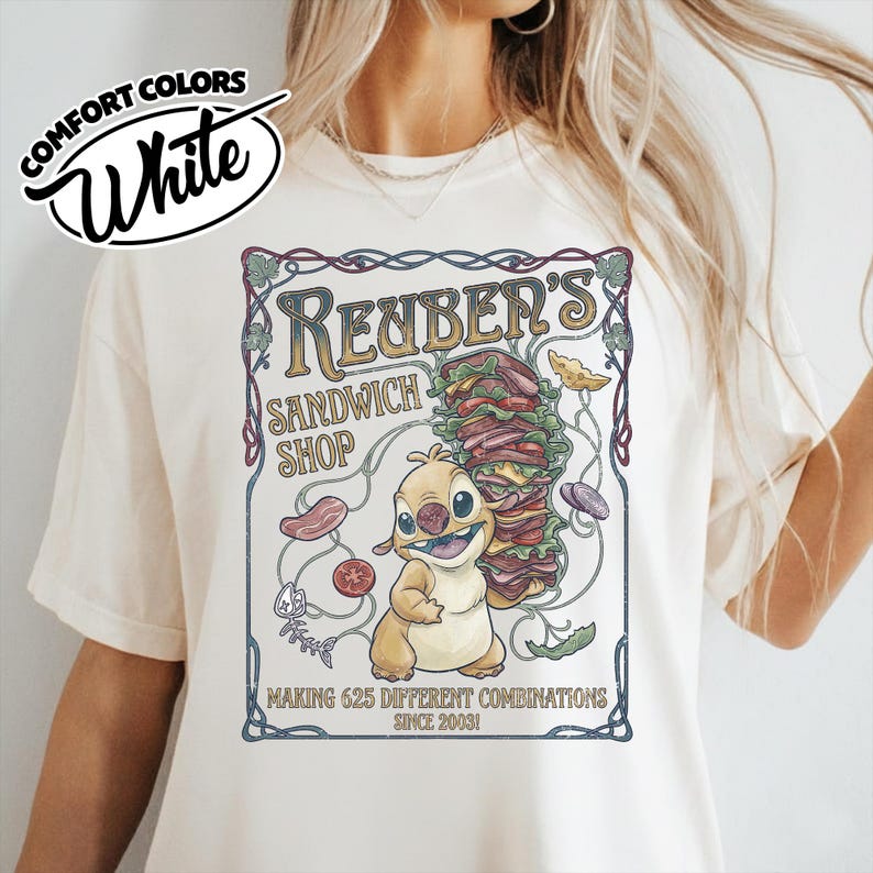 K&ouml;nnte beinhalten: Wei&szlig;es Comfort Colors T-Shirt mit einem Aufdruck f&uuml;r Reuben's Sandwich Shop. Das Design zeigt eine Cartoonfigur, die ein gro&szlig;es Sandwich h&auml;lt, mit dem Text "MAKING 625 DIFFERENT COMBINATIONS SINCE 2003!"