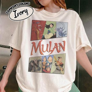Puede incluir: Camiseta de color marfil con un dise&ntilde;o gr&aacute;fico de la pel&iacute;cula de animaci&oacute;n Mulan. El dise&ntilde;o incluye el t&iacute;tulo de la pel&iacute;cula e ilustraciones de personajes en un dise&ntilde;o rectangular. La camiseta tiene mangas cortas y cuello redondo.