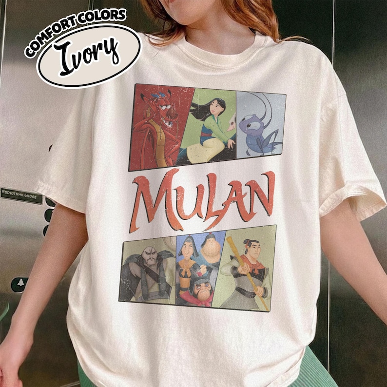 Puede incluir: Camiseta de color marfil con un dise&ntilde;o gr&aacute;fico de la pel&iacute;cula de animaci&oacute;n Mulan. El dise&ntilde;o incluye el t&iacute;tulo de la pel&iacute;cula e ilustraciones de personajes en un dise&ntilde;o rectangular. La camiseta tiene mangas cortas y cuello redondo.