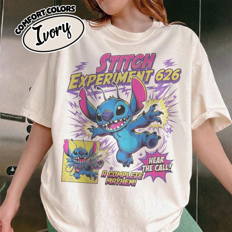 Może przedstawiać: Koszulka w kolorze kości słoniowej z grafiką niebieskiej postaci Stitcha z Experiment 626. Projekt zawiera tekst STITCH EXPERIMENT 626, HEAR THE CALL oraz A COMPLETE MAYHEM, wraz z mniejszym wstawionym obrazkiem postaci.