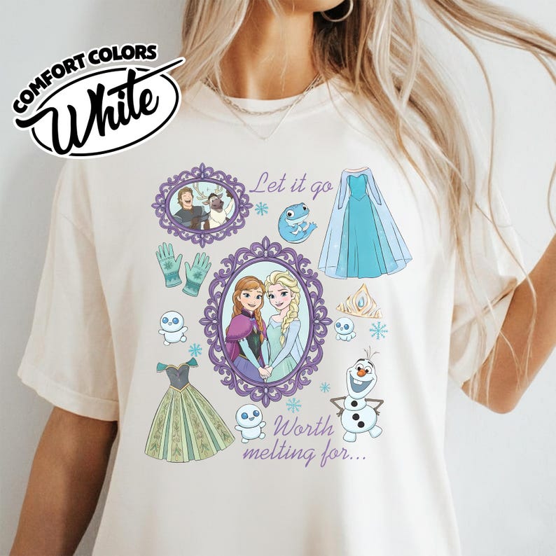 Op de afbeelding: Wit Comfort Colors T-shirt met een grafisch ontwerp met personages en elementen uit de film. Het ontwerp bevat ingelijste portretten, jurken, sneeuwvlokken en de tekst "Let it go" en "Worth melting for..."
