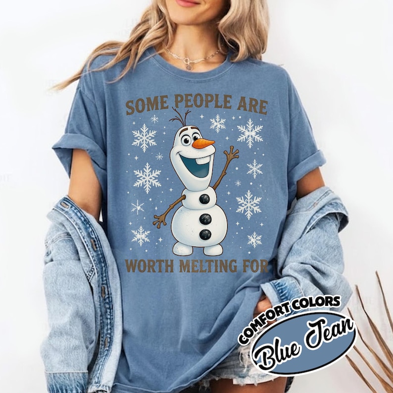 May include: Blue t-shirt with the text "SOME PEOPLE ARE WORTH MELTING FOR" and a cartoon Olaf character. The shirt also features snowflake graphics. The shirt is a Comfort Colors brand in Blue Jean.