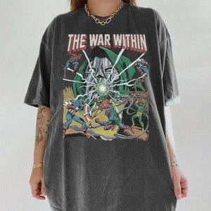 May include: Dark gray t-shirt with a graphic featuring comic book characters and the text "THE WAR WITHIN" in red and white. The design includes Captain America, Spider-Man, and Doctor Doom. The shirt has short sleeves and a relaxed fit.