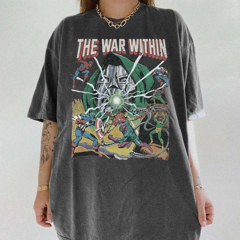 May include: Dark gray t-shirt with a graphic featuring comic book characters and the text "THE WAR WITHIN" in red and white. The design includes Captain America, Spider-Man, and Doctor Doom. The shirt has short sleeves and a relaxed fit.