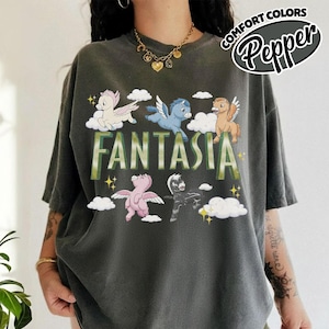 May include: Dark grey t-shirt featuring the word "FANTASIA" in green, with cartoon pegasus characters. The shirt also has the words "COMFORT COLORS" and "Pepper" in a circular design.