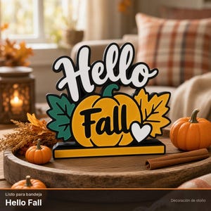 Puede incluir: Un letrero decorativo de mesa con el texto Hello Fall en letra cursiva negra y blanca. El diseño incluye una calabaza amarilla central, una hoja verde, una hoja amarilla y un pequeño corazón blanco sobre una base negra rectangular.