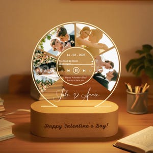 Puede incluir: Un regalo personalizado para el Día de San Valentín. Presenta una pantalla fotográfica circular con múltiples imágenes, los nombres "Jake & Annie", y el texto "Happy Valentine's Day!". Incluye una interfaz de reproductor de música con la canción "You Rock My World".
