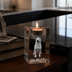 Puede incluir: Un portavelas rectangular de cristal transparente con una imagen grabada de un perro sentado. El nombre Bella y la fecha 2025.10.06 están grabados debajo del perro. Una vela de té encendida descansa en la hendidura circular superior.