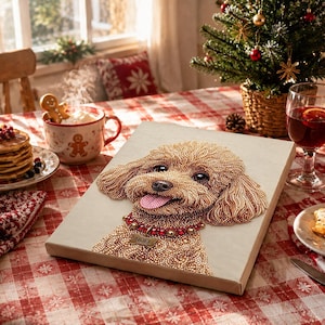 Puede incluir: Un lienzo de pintura de diamantes que muestra a un perro de pelo rizado color marrón claro con la lengua rosa, usando un collar rojo con una placa dorada que dice NOEL. La obra está sobre un mantel de cuadros rojos y blancos.
