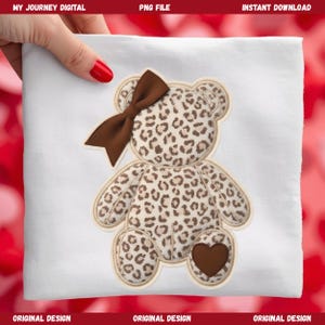 May include: A white fabric with a leopard print teddy bear applique. The bear has a brown bow, a heart-shaped patch, and is outlined in a light brown color. The text "MY JOURNEY DIGITAL" and "PNG FILE" are at the top.