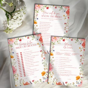 May include: Three white paper wedding game cards featuring floral borders with pink, orange, and blue flowers. The cards are titled How Well Do You Know The Bride, Guess Who Bride Or Groom, and Movie Quotes, each with printed questions and lines.