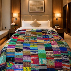 May include: A vibrant patchwork quilt adorns a bed in a hotel room. The quilt features a multitude of fabric squares in hues of blue, green, red, and yellow. The bed is dressed with white pillows and a neutral headboard.