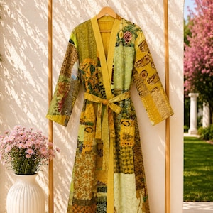 May include: A long-sleeved robe featuring a patchwork design in various shades of yellow, olive green, and brown. The garment includes a solid yellow collar, a matching tie belt at the waist, and two front pockets, all constructed from quilted fabric.