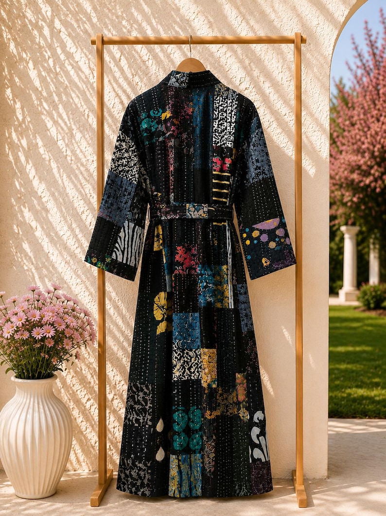 May include: A long-sleeved robe featuring a patchwork design with various colorful patterns on a dark base. The garment includes a matching tie belt at the waist and is constructed with visible vertical stitching throughout the fabric.