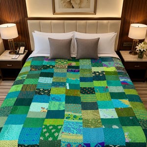 Puede incluir: Un edredón de retazos en tonos verdes y azules cubre una cama. El edredón está hecho de varios cuadrados de tela, creando un diseño texturizado y colorido. La cama está hecha con almohadas blancas y un cabecero neutro.