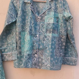 Peut inclure: Ensemble de pyjama bleu sarcelle à motifs cachemire. Le haut à manches longues a un col cranté, une poche poitrine et une bordure blanche. Le tissu est un motif patchwork avec des détails cachemire blancs.