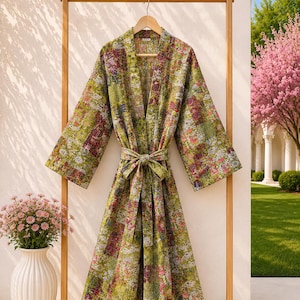 Könnte beinhalten: Ein langärmeliger Morgenmantel mit einem lebendigen Patchwork-Muster in Olivgrün, Pink und Weiß. Das Kleidungsstück verfügt über einen passenden Bindegürtel in der Taille, weite Ärmel und einen geraden Saum mit sichtbaren Steppnähten.
