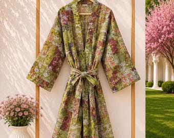 May include: A long-sleeved robe featuring a vibrant patchwork pattern in shades of olive green, pink, and white. The garment includes a matching tie belt at the waist, wide sleeves, and a straight hemline, constructed with visible quilted stitching.