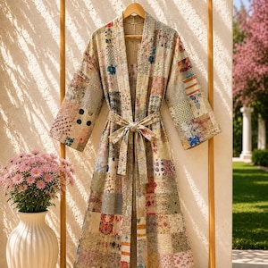 May include: A long-sleeved robe featuring a patchwork design composed of various fabric squares in muted tones of beige, tan, and cream, accented with small floral, polka dot, and geometric patterns. The robe includes a matching fabric tie belt.