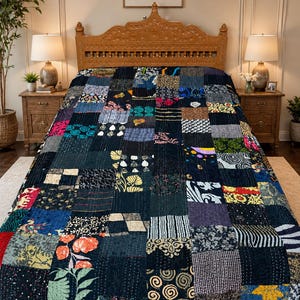 Könnte beinhalten: Eine Patchwork-Steppdecke mit dunkelblauem Grund, die eine Vielzahl farbenfroher Stoffquadrate aufweist. Die Quadrate zeigen florale, geometrische und abstrakte Muster in Orange-, Grün-, Weiß- und Schwarztönen. Die Steppdecke liegt auf einem Bett.
