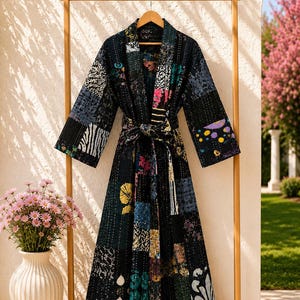 May include: A long-sleeved robe featuring a patchwork design with various dark-toned fabric squares. The garment includes a matching tie belt at the waist, a shawl collar, and visible white stitching throughout the quilted, multi-patterned textile.