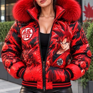 Op de afbeelding: Een rood met zwarte donsjas met een grote capuchon en een rand van rood imitatiebont. De jas is voorzien van een grafische print van een personage met stekelig haar, oranje drakenbalmotieven en het Japanse kanji-symbool voor wijsheid in witte cirkels.