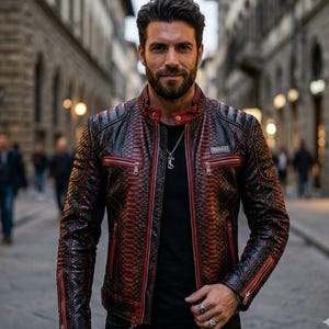 May include: A black and red snakeskin-patterned leather jacket with red zipper trim and the word "SNAKE" on a small patch. The jacket has a quilted design on the shoulders and is worn over a black shirt.