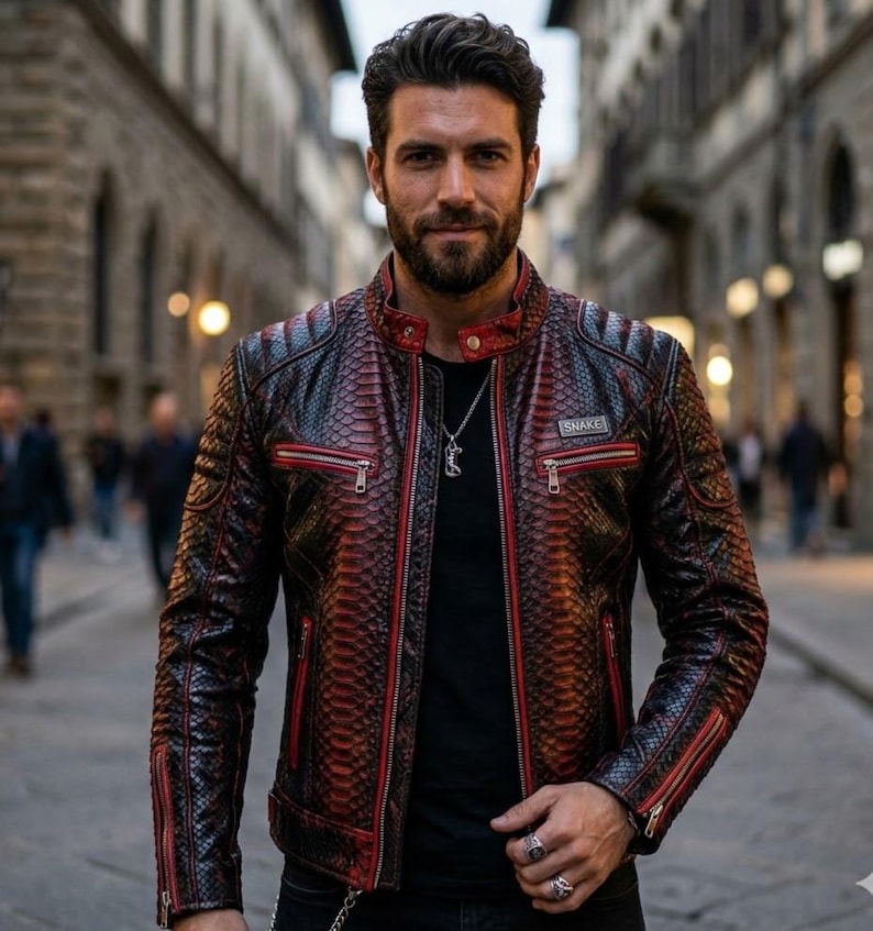 May include: A black and red snakeskin-patterned leather jacket with red zipper trim and the word "SNAKE" on a small patch. The jacket has a quilted design on the shoulders and is worn over a black shirt.