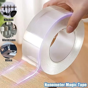 Puede incluir: Un rollo de cinta adhesiva de doble cara transparente Nanometer Magic Tape. La cinta está siendo sostenida por una mano y está parcialmente desenrollada, revelando su cualidad adhesiva. La imagen también muestra los usos potenciales de la cinta en la cocina, el baño y la oficina.