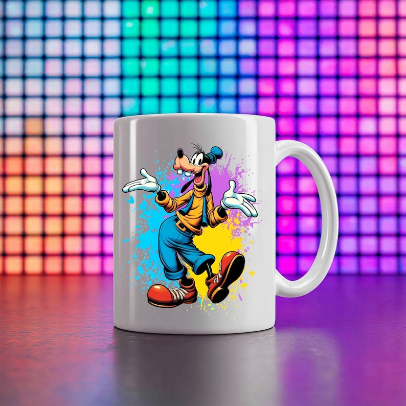 May include: A white ceramic mug featuring a colourful graphic of the cartoon character Goofy. The character is depicted with a yellow shirt, blue trousers, and large red shoes, set against a vibrant splash of blue, purple, and yellow paint splatters.