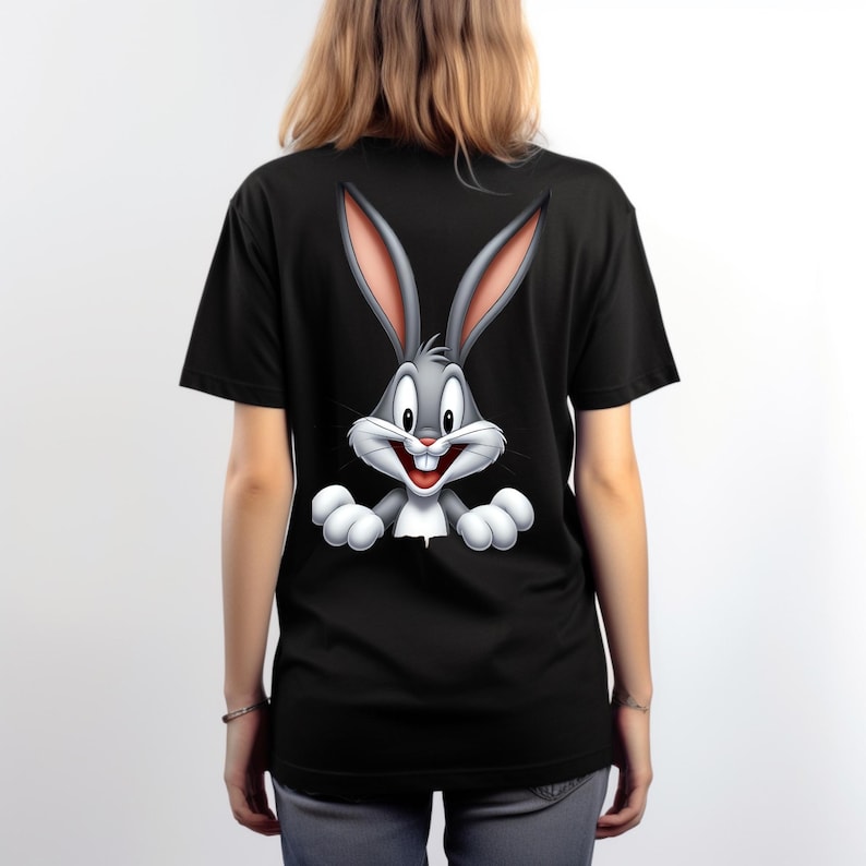 May include: A black short-sleeved t-shirt featuring a large, centred graphic of the cartoon character Bugs Bunny. The character is depicted with long grey ears, a white muzzle, and white paws, appearing as if peeking over the bottom of the design.