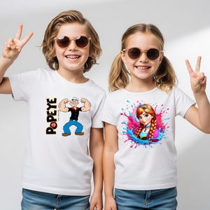 May include: Two white short-sleeved t-shirts worn by children. The left shirt features a graphic of Popeye the Sailor with the text POPEYE. The right shirt displays a colourful graphic of the character Anna surrounded by pink and blue paint splashes.