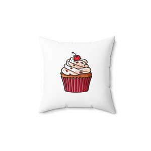 Peut inclure: Coussin carré blanc avec un motif de cupcake de dessin animé. Le cupcake a une base rouge et marron, un glaçage blanc avec des vermicelles rouges et une cerise sur le dessus. Article décoratif.